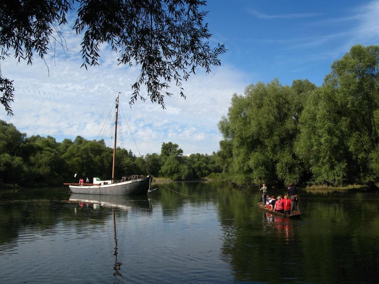 "Heini" dokumentiert als Museumsschiff ein wichtiges Kapitel oberrheinischer Fischereigeschichte und kann als Station auf dem PAMINA-Rheinpark-Fahrradweg zu besonderen Terminen besichtigt werden, Foto: Oliver Hurst. Gruppe von Besuchern setzten in einem Boot auf den Aalschokker über.