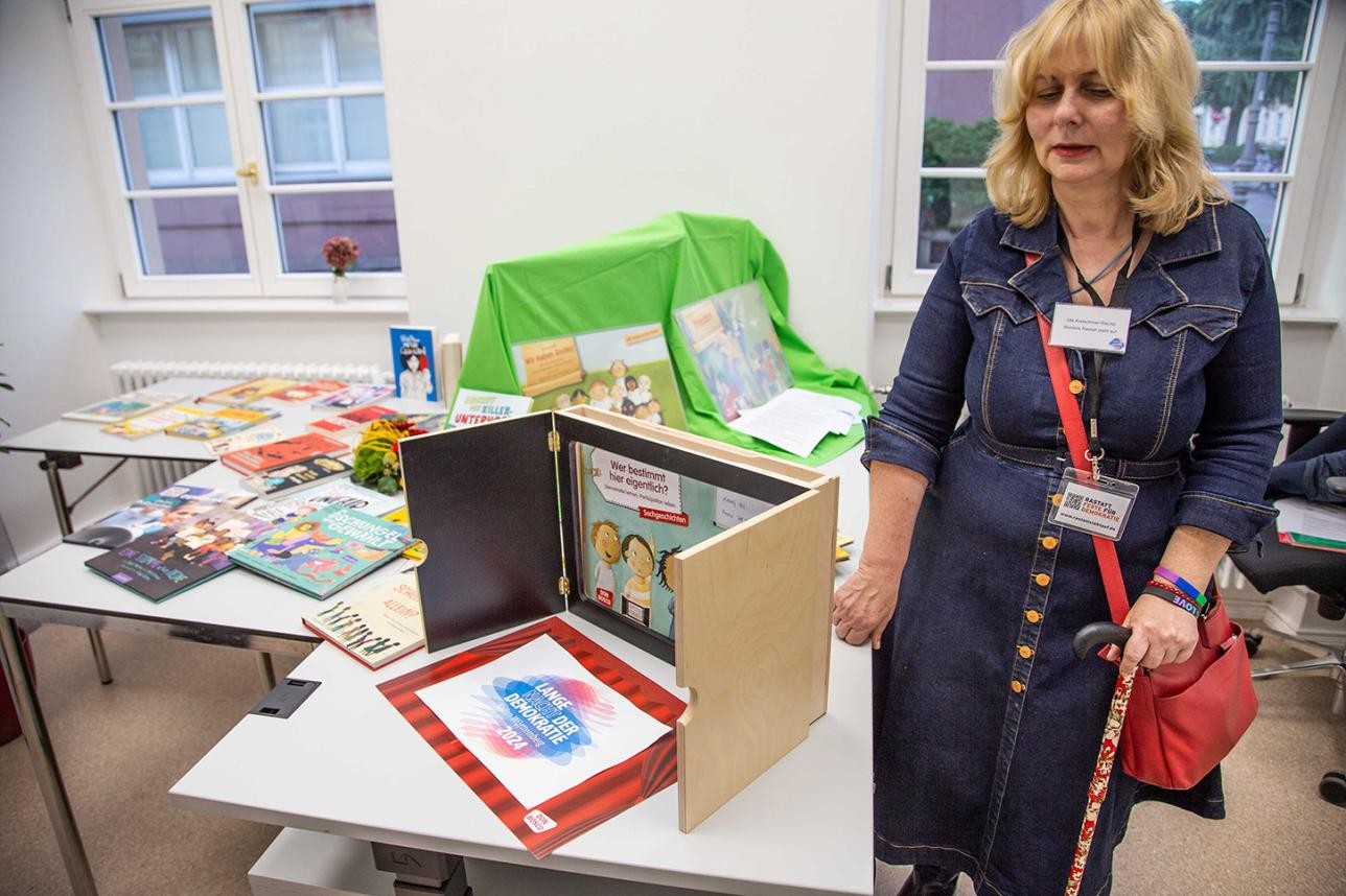 In der Bücherstube Bücherschau für Kinder und Jugendliche zum Thema Demokratie. Foto: Günter Kunz Frau steht neben Büchern auf einem Tisch