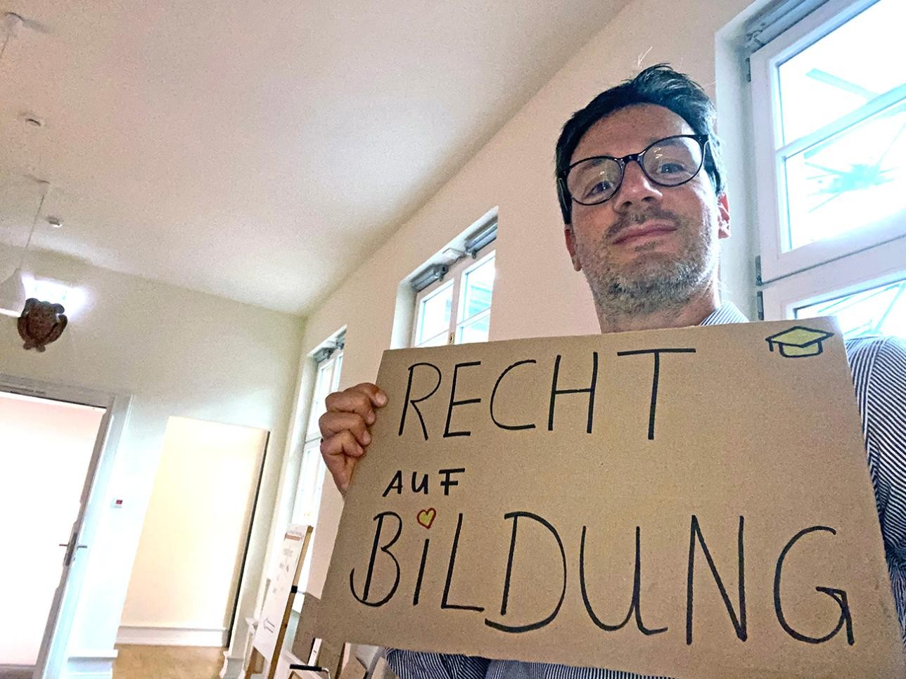 Ein sogenanntes „Grulfie“ – Handyslefie mit einem Begriff aus unserem Grundgesetz . Foto: Miguel Rodriguez Mann macht ein Selfie mit einem Schild in der Hand