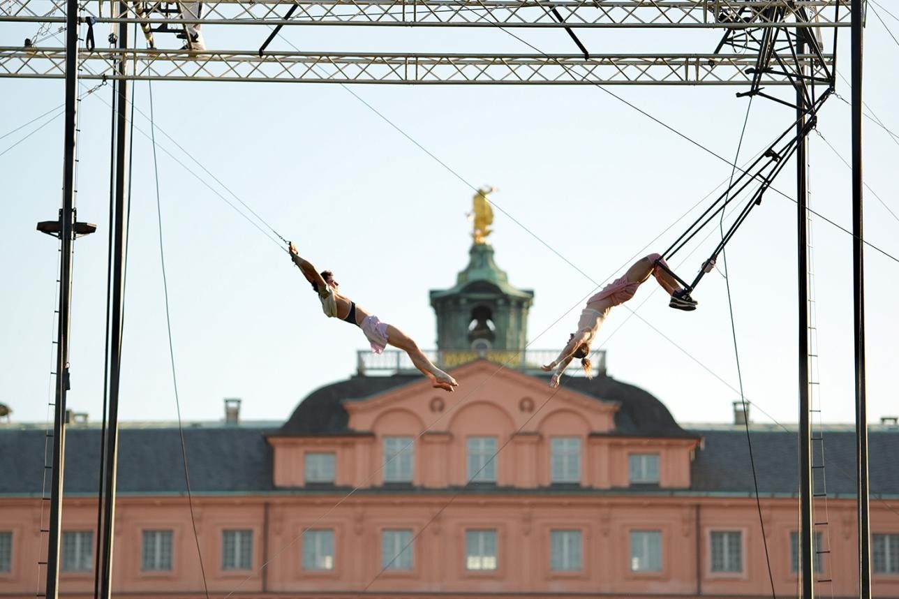 Straßenkunst vom Feinsten: Das tête-à-tête 2026 zog auch in diesem Jahr wieder zehntausende Besucherinnen und Besucher an. Fotos: Jakob Sax Künstler schaukeln an einem Trapez vor der Schlosskulisse